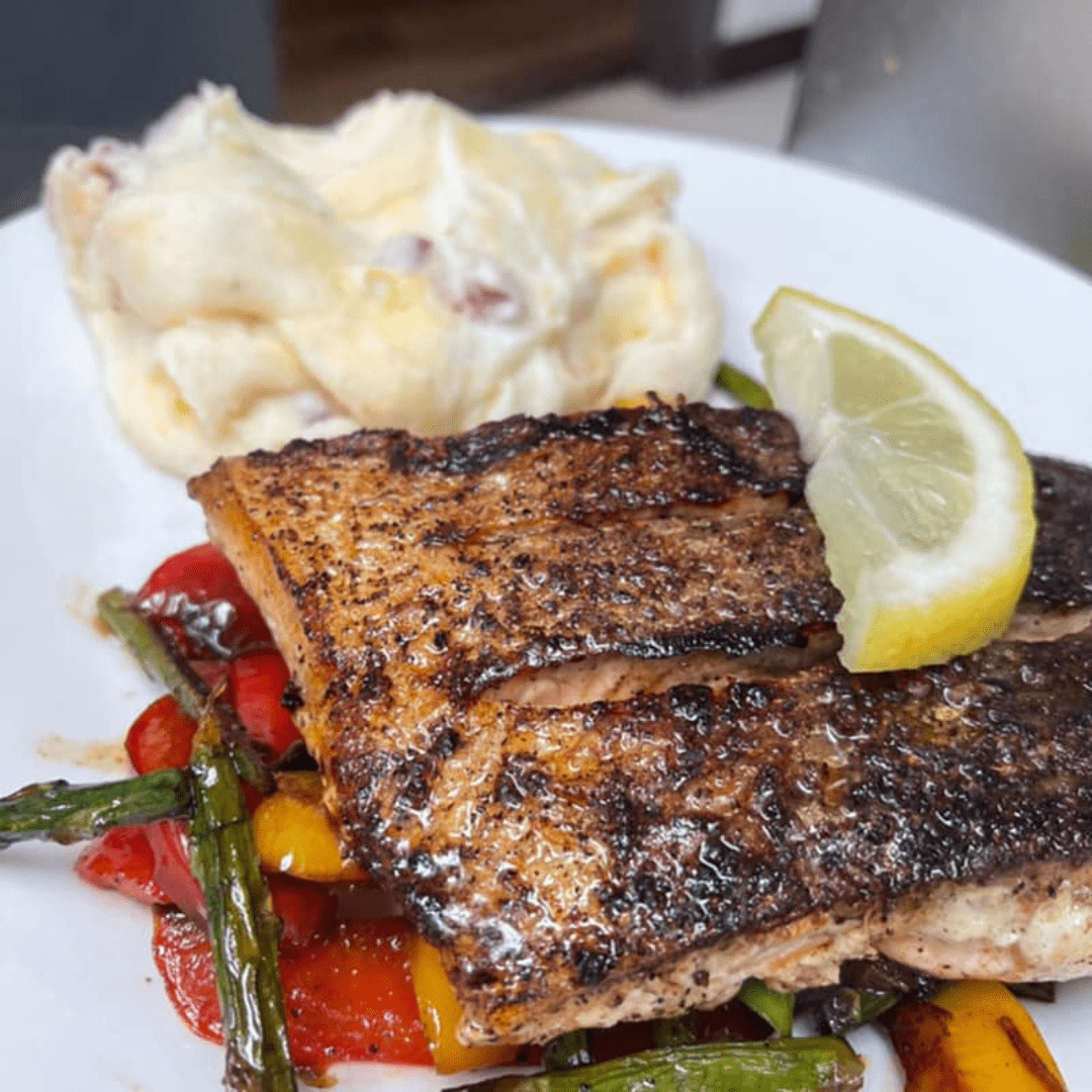 Grilled salmon served with asparagus and peppers on a white plate from Bill's Grill in Downtown Wilson.