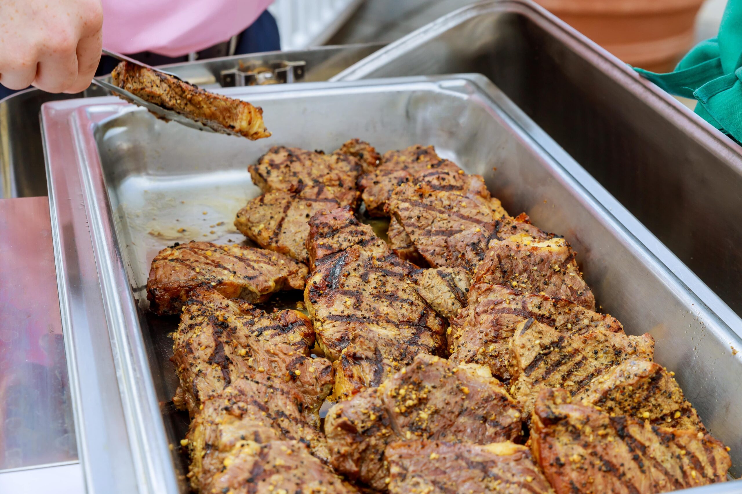 Juicy rib eye beef steaks seasoned with spices, displayed on a tray, ready for barbecue.