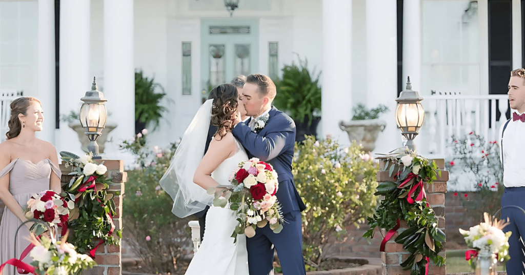 A newlywed couple shares a kiss at a beautifully decorated wedding venue in Greenville, NC.