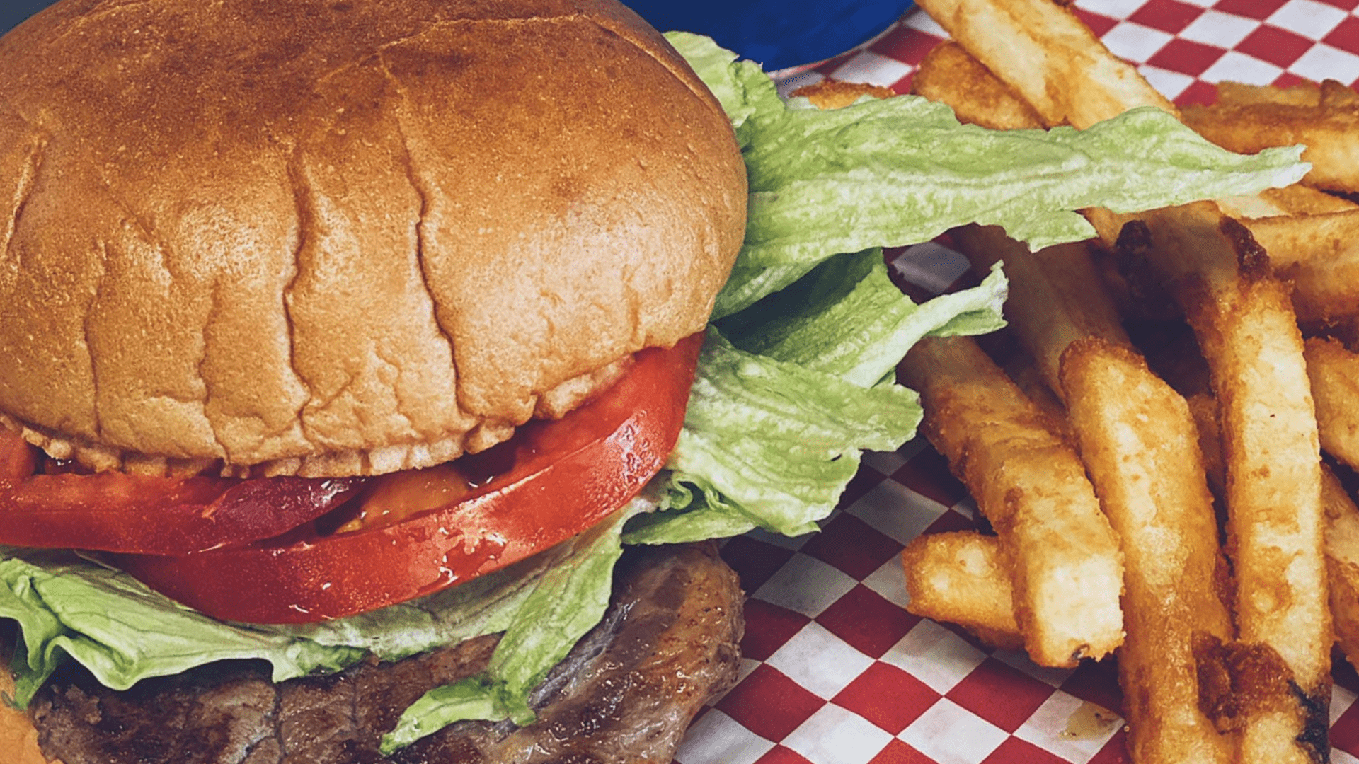 A classic hamburger with french fries and a Pepsi, served on a checkered table.