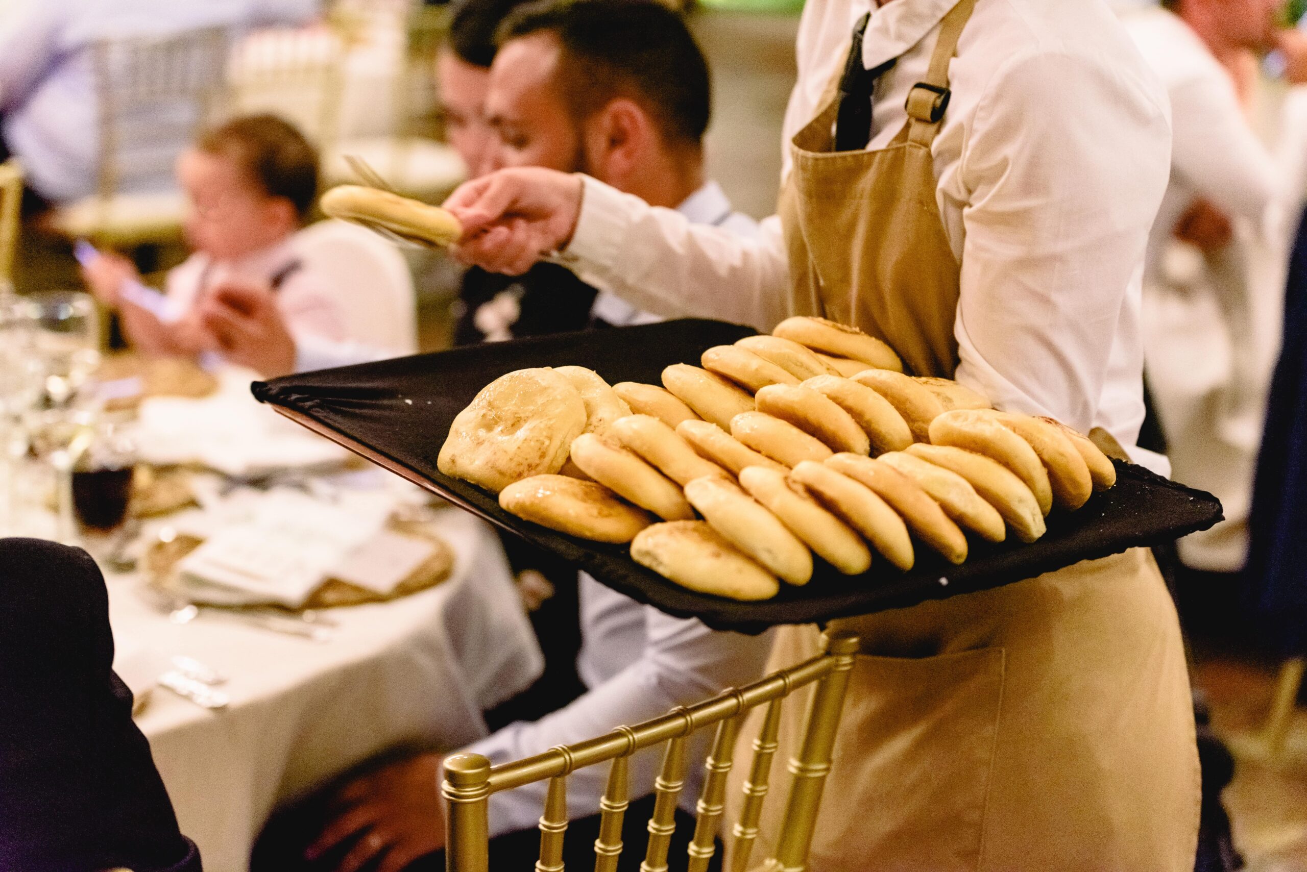 A waitress serving freshly baked bread to guests during a catering event.