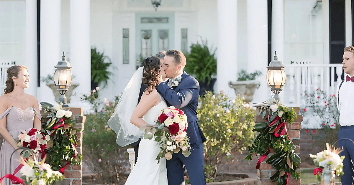 A newlywed couple shares a kiss at a beautifully decorated wedding venue in Greenville, NC.