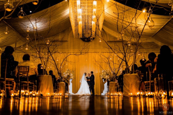 A beautifully decorated wedding ceremony at Rock Springs Center in Greenville, NC, with warm lighting and luxurious decor.