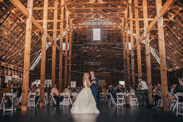 A bride and groom share their first dance at a rustic barn wedding venue in Greenville, NC, surrounded by family and friends.